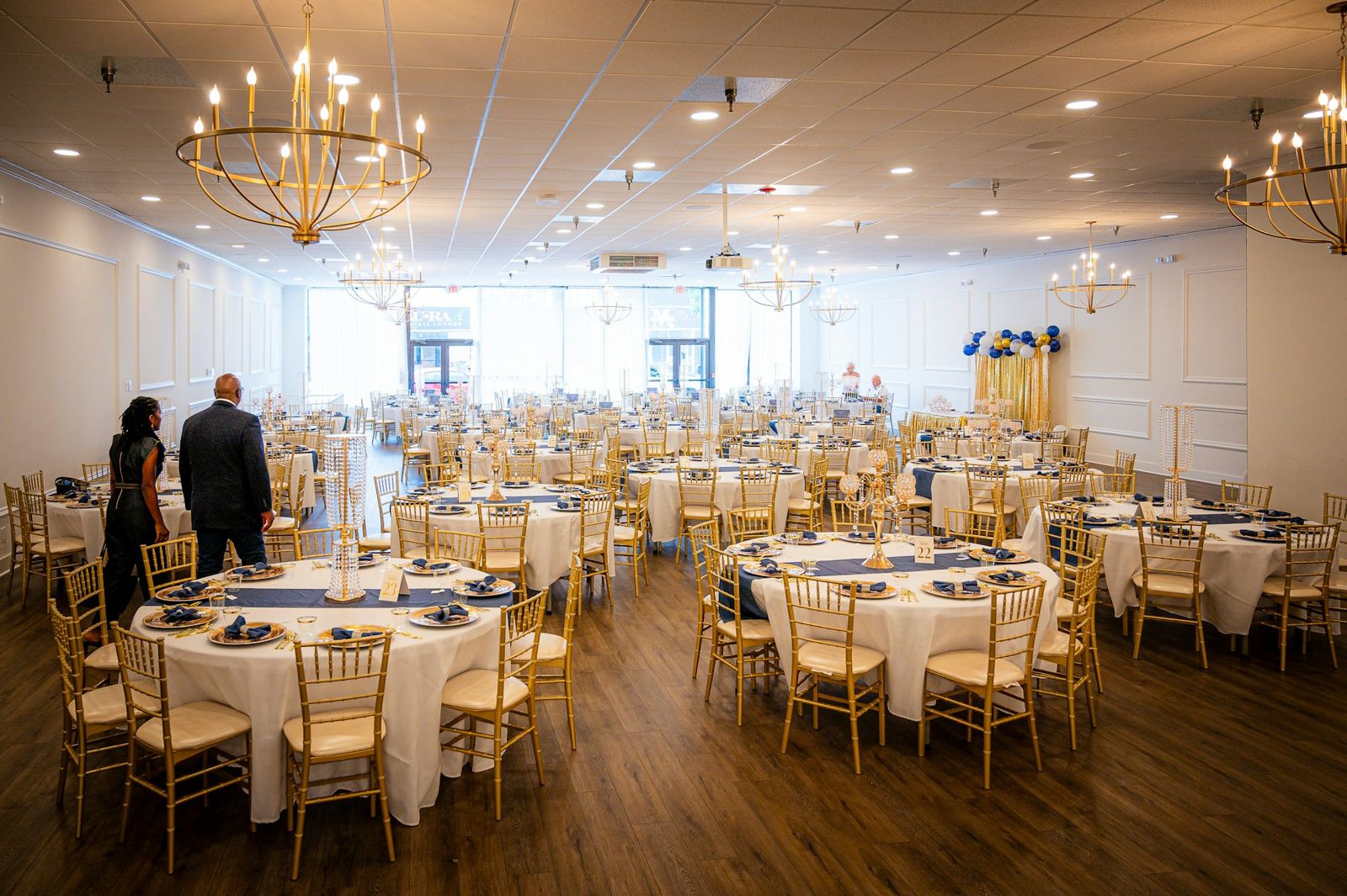 A banquet hall set with round tables and chandeliers